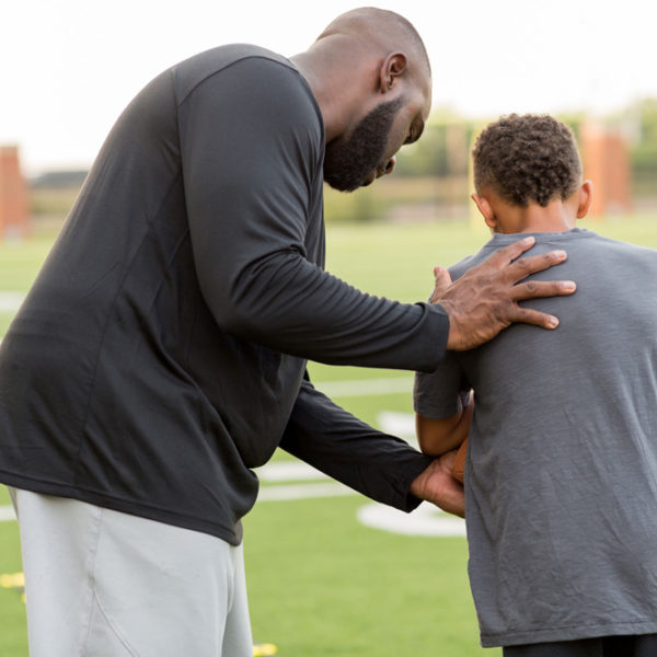 American Football coach teaching and training a young athlete